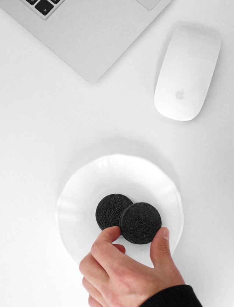 A plate of cookies is next to a laptop and mouse